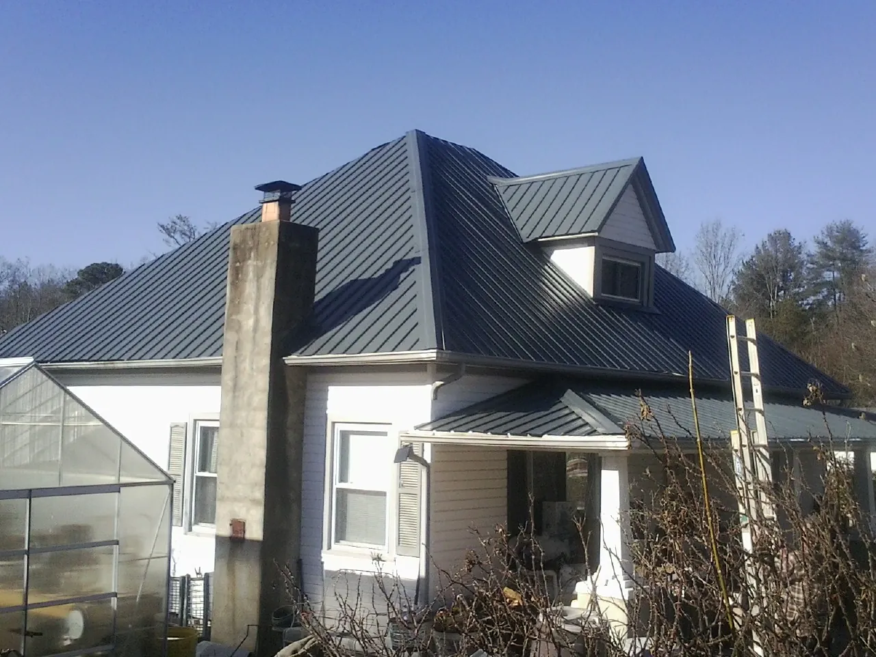 Dark blue standing seam metal roof on a white farmhouse with dormer — Slate & Tile Roof Repair by Roofing Brothers in West Boylston