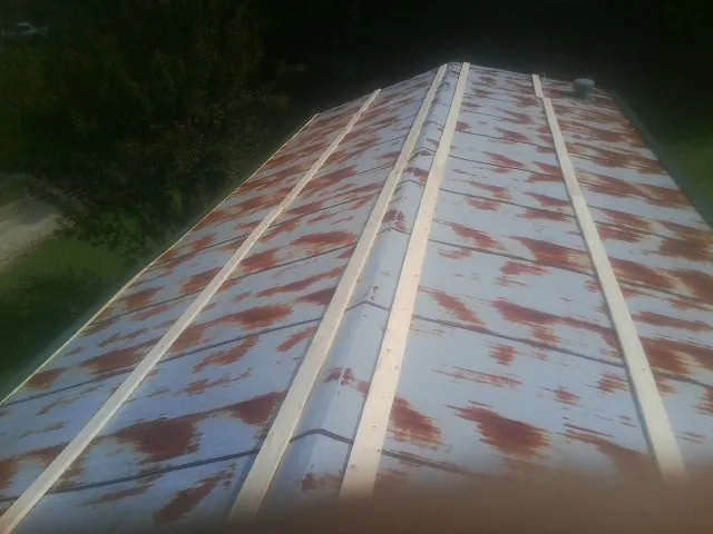 Rusted metal roof panels with new wood purlins before replacement — Storm Damage Roof Repair in West Boylston by Roofing Brothers