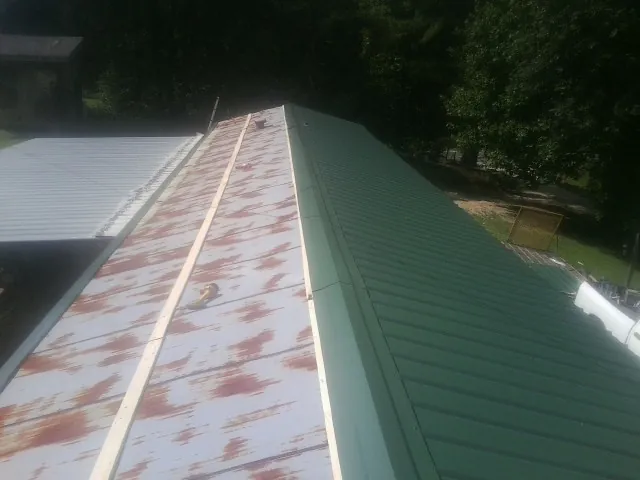 Old rusted panels beside newly installed green metal roofing — Wind Damage Roof Repair by Roofing Brothers in West Boylston