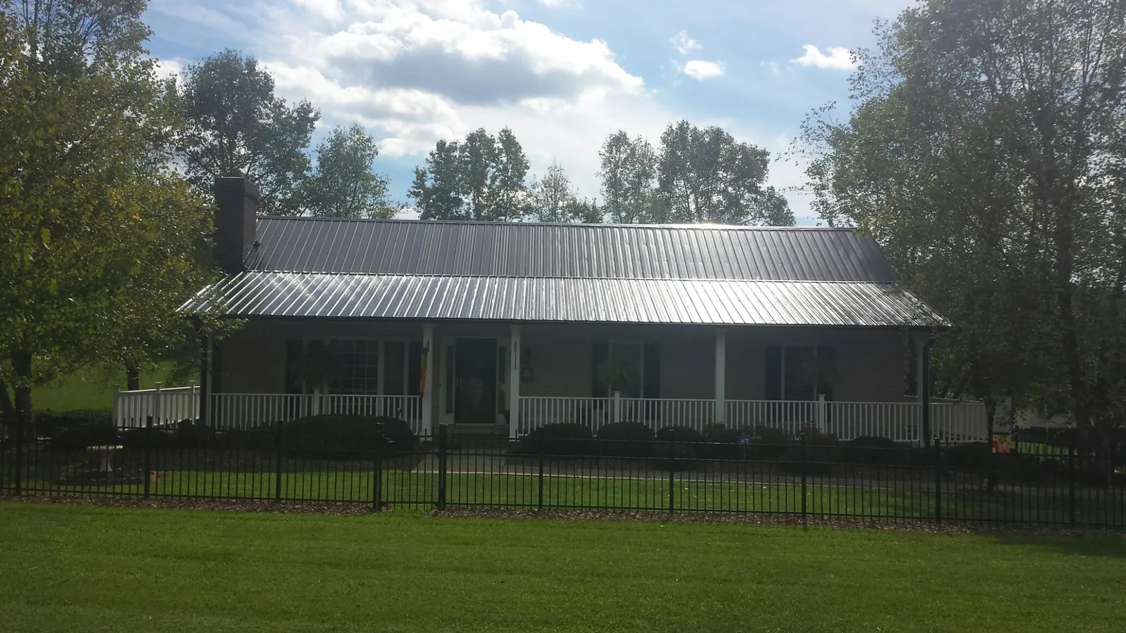 Gray metal roof on a brick ranch with a full width front porch — Gutter Guard Installation work by our crew in West Boylston