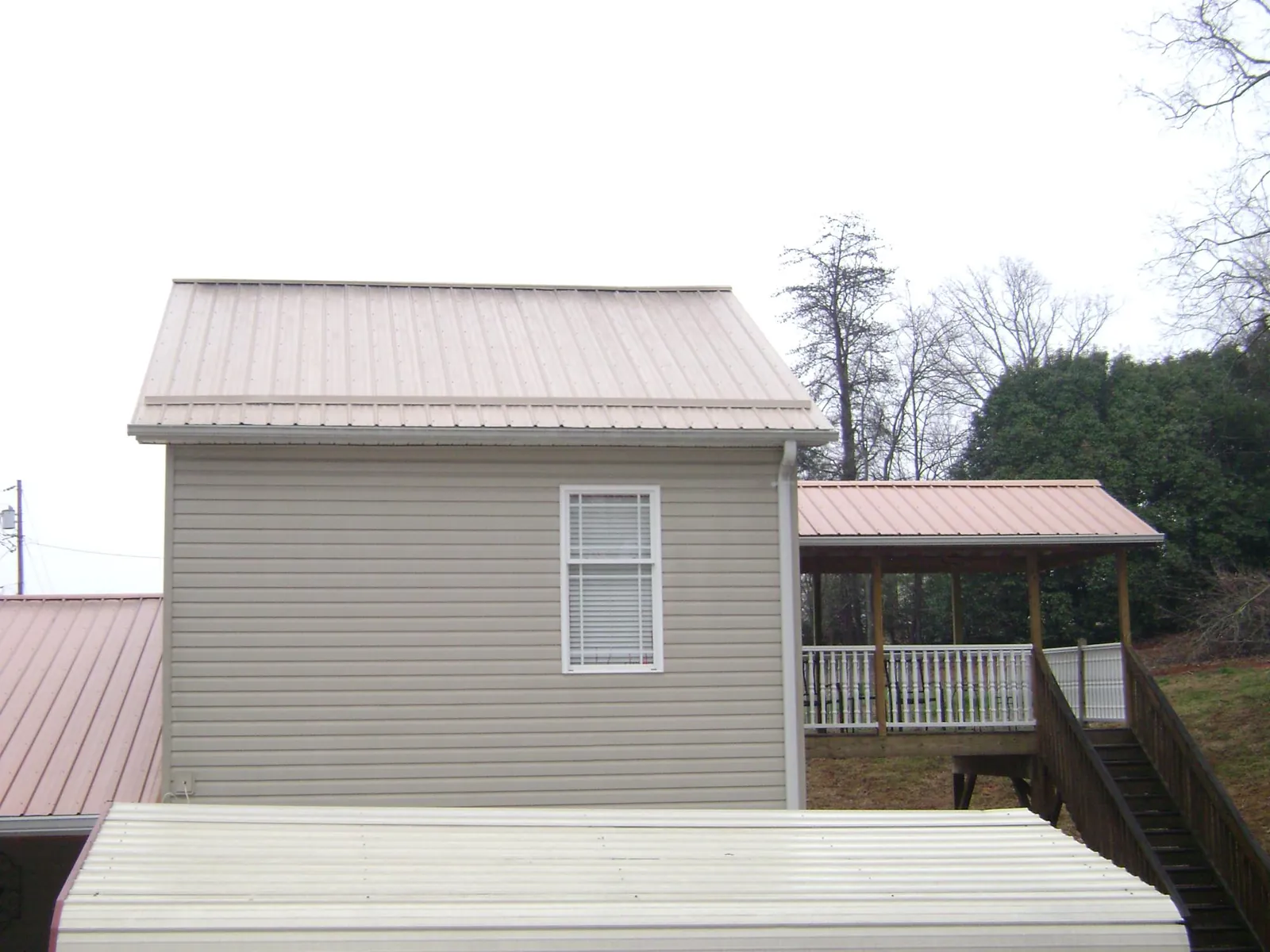 Tan metal roofs on a two story addition and attached porch, from a Roof Replacement job in West Boylston