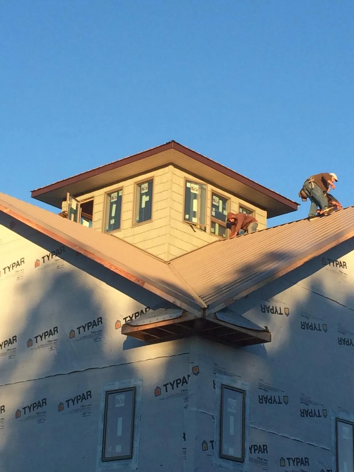 Roofers working around a rooftop cupola on a new metal roof at sunset — Roof Waterproofing in West Boylston by Roofing Brothers